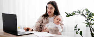 Working Mom mit Baby auf dem Arm am Laptop